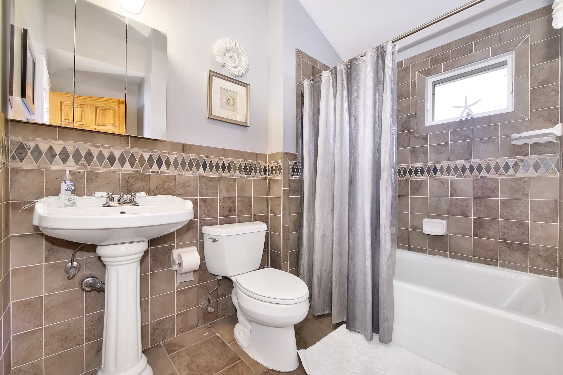 Tiled bathroom with pedestal sink and tub
