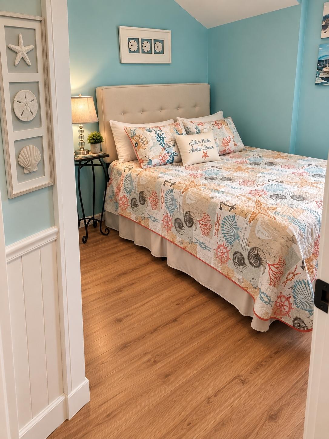 Bedroom with upholstered headboard and nautical-print quilt