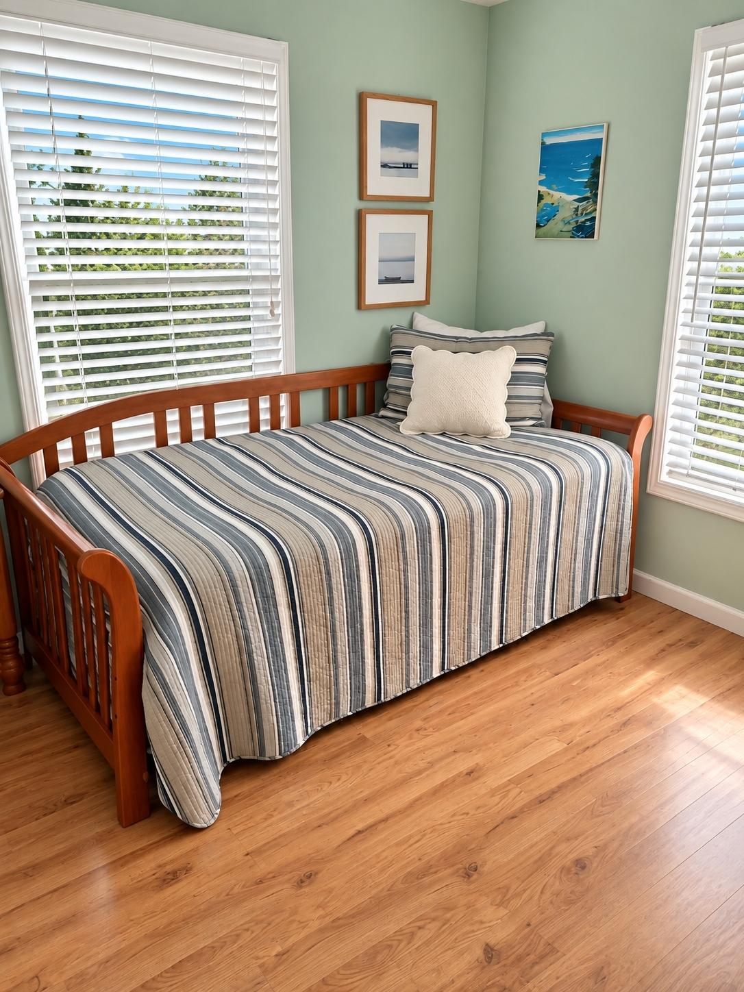 Corner daybed with striped quilt and coastal wall art